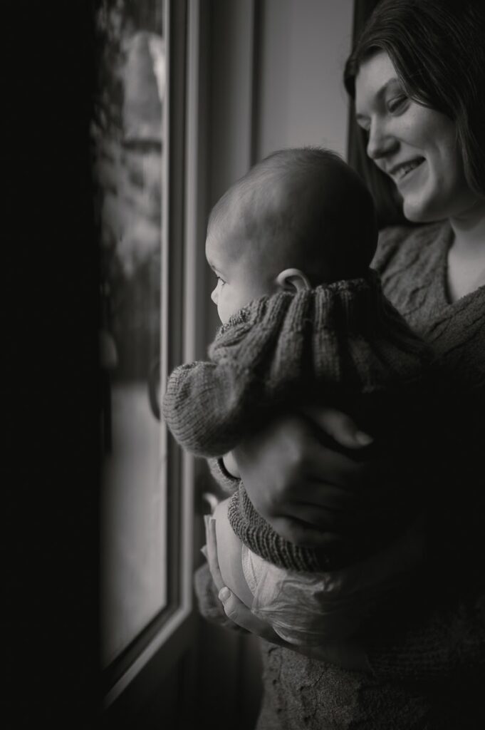 Mamman och bebisen står framför ett fönster och tittat ut.