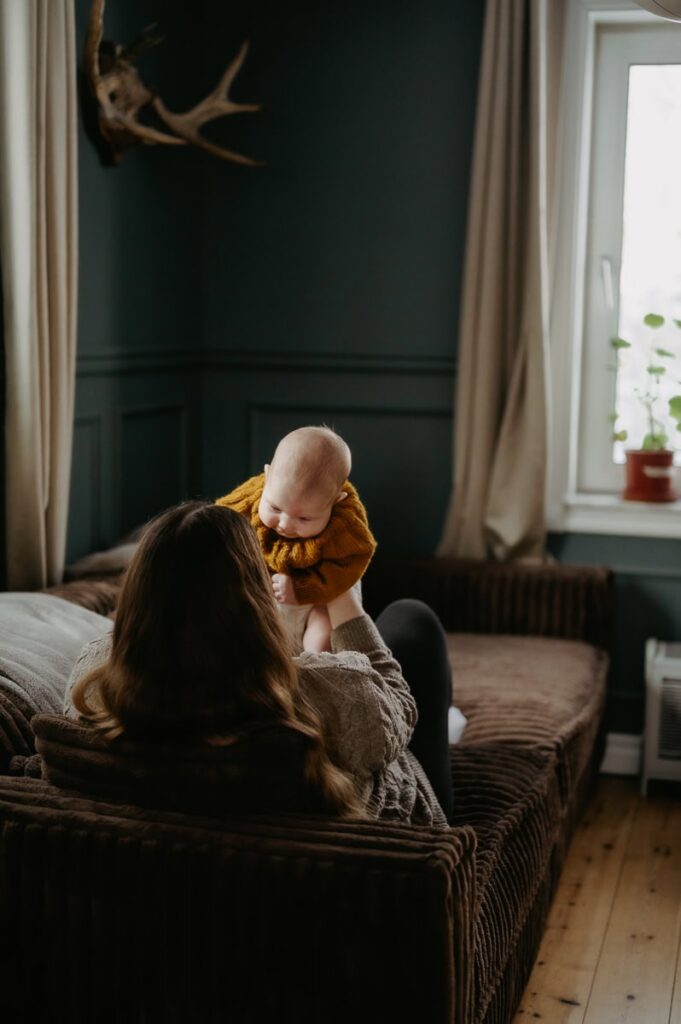 Bebisen sitter i sin mammas knä och myser.
