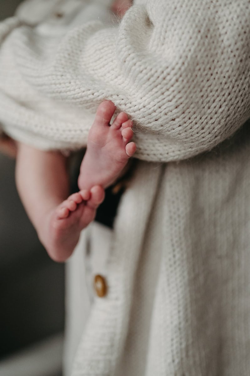 Bebis fötter sticker fram i mammans famn.