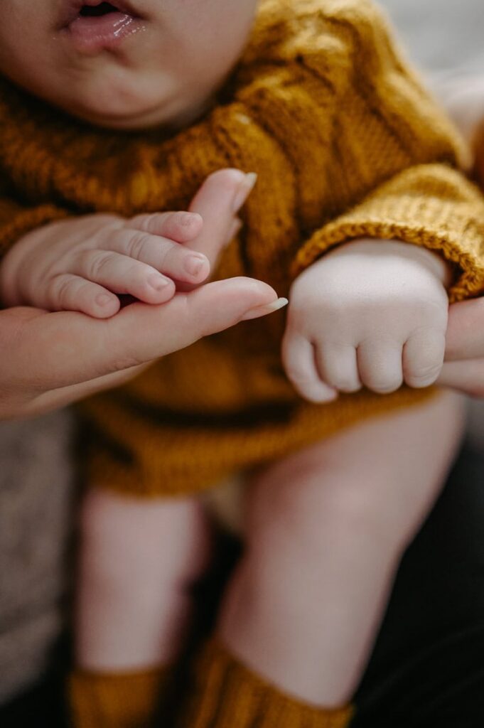 Närbild på bebisens händer som ligger i sin mammas händer.
