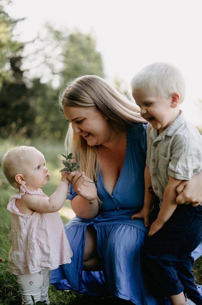 Mamma sitter med sina två barn och har plockat en rödklöver.