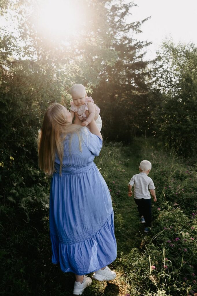 Mamma håller upp sin bebis i luften en fin sommarkväll.