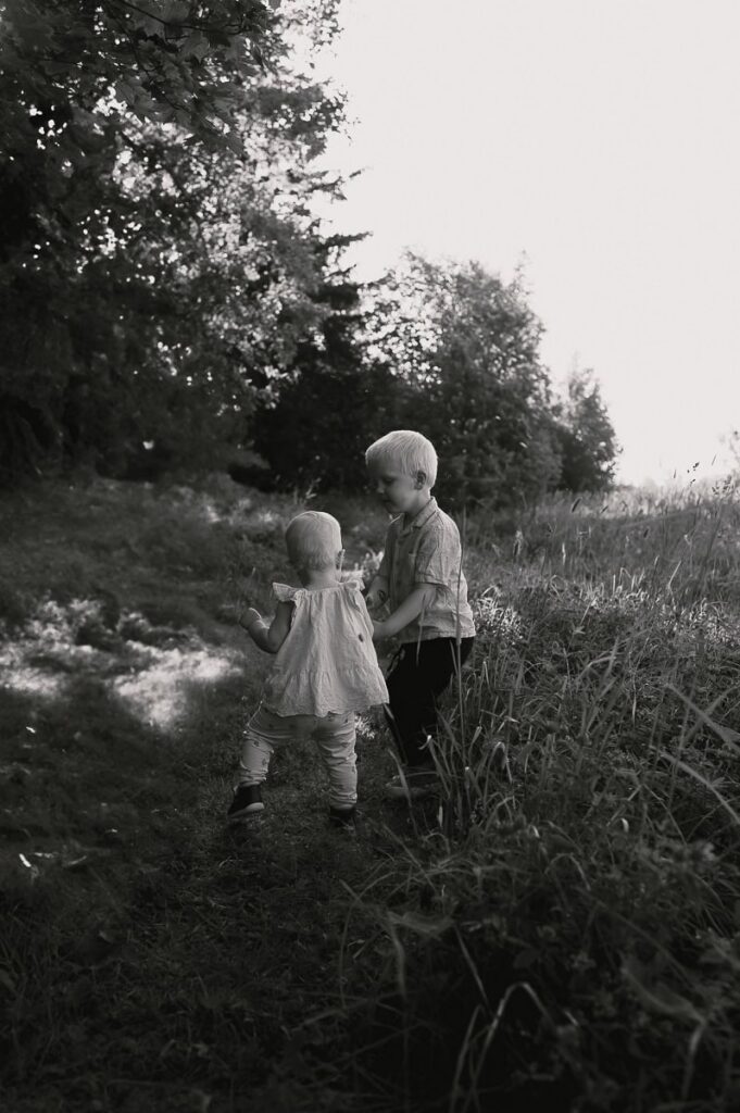 Två syskon håller handen i gröngräset.