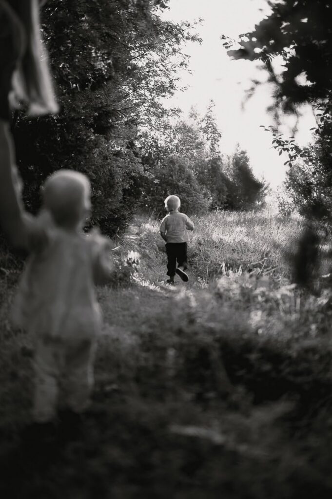 Barn springer på en stig och lillasyster följer efter.
