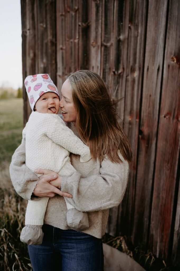 Mamma håller sin bebis i famnen vid en vägg.