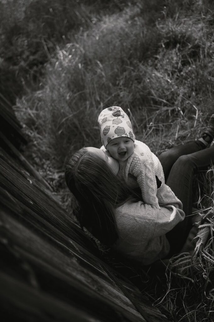 Bebis och mamma sitter i gräset och gosar.