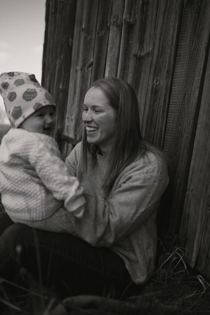 Bebis och mamma sitter i gräset och skrattar.