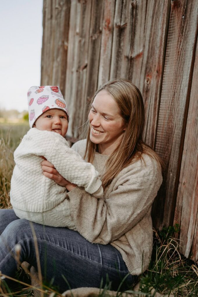 Bebis sitter i sin mammas knä och skrattar.